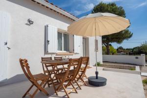 drewniany stół i krzesła z parasolem w obiekcie Villa provençale proche mer au calme w mieście Martigues