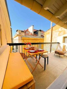 a balcony with a table and benches on a balcony at Beautiful Top Floor & Terrasse (Beach 1' walk) in Nice
