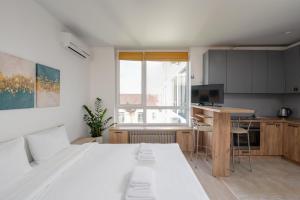 a bedroom with a large white bed and a kitchen at Nyvky Residence in Kyiv