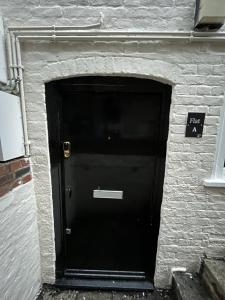 uma porta preta num edifício de tijolos com um sinal em The Cozy Apartment em Gloucester