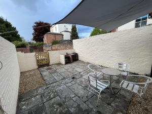 un patio con mesa, sillas y una valla en The Cozy Apartment en Gloucester