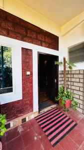 a red brick building with a door and a rug at Sana Estate Stay in Madikeri