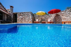 a swimming pool with two umbrellas and chairs at Villa Lily Comfortable holiday residence in Veli Iž