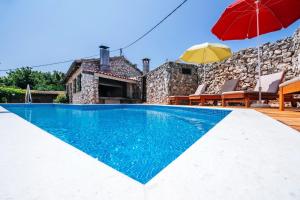 a villa with a swimming pool and a red umbrella at Villa Lily Comfortable holiday residence in Veli Iž