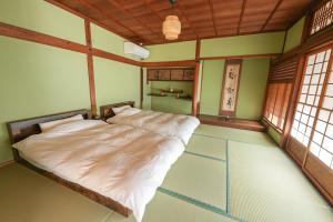 1 dormitorio con 1 cama en una habitación con ventanas en 奥明日香古民家一棟貸し宿 弥栄 Yasaka, en Asuka