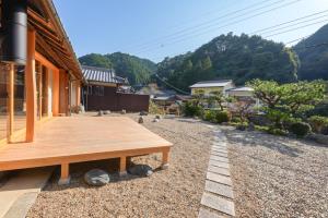 un banco de madera sentado fuera de una casa en 奥明日香古民家一棟貸し宿 弥栄 Yasaka, en Asuka