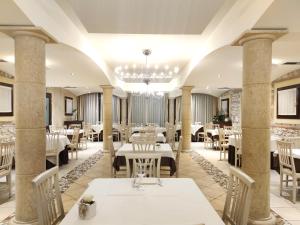 um restaurante com mesas e cadeiras brancas e um lustre em Tenuta Albertini em Zevio