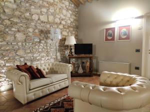 a living room with two white couches and a stone wall at Tenuta Albertini in Zevio