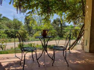 einen Tisch und zwei Stühle auf einer Veranda mit einer Vase darauf in der Unterkunft Bastide gecko doré in Cotignac