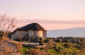 una casa antigua con techo de paja en una colina en MANİCİ ÇİFTLİK en Ayvacık