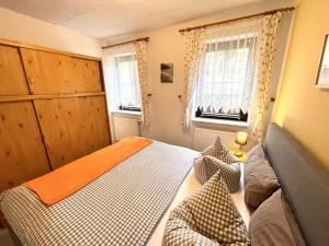 a small bedroom with a bed and two windows at Pension Schanzenblick in Kurort Oberwiesenthal