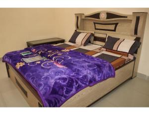 a large bed with a purple blanket on it at Hotel Poornima Palace, Fatehpur in Fatehpur