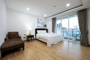 a bedroom with a bed and a chair and a window at Olympia City Residence Suite by Caerus Management in Phnom Penh