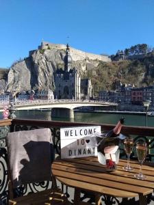 un banco con un cartel de bienvenida y copas de vino en Appartement The View en Dinant