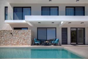 a house with two chairs and a swimming pool at Villa Blauw with Infinity Pool & Sea Views in Vasiliki