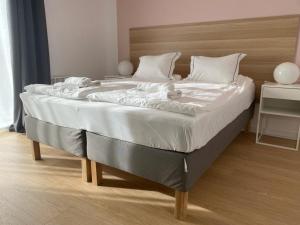 a large bed with white sheets and a wooden headboard at Apartamenty przy Winnicy in Busko-Zdrój