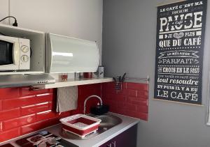 a kitchen with a sink and a red brick wall at Jolie studio 10min centre ville et 300m quai de seine WIFI in Rouen