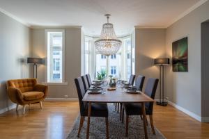 una sala da pranzo con tavolo, sedie e lampadario pendente di Enter Tromsø - 3 Bedroom Luxury Apartment a Tromsø