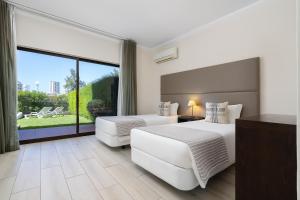 Una habitación de hotel con dos camas y una gran ventana. en Clube Vilarosa, en Portimão 37 fotos más
