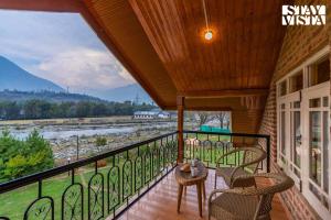 balcón con vistas al río y a las montañas en StayVista at Qaraar - Preng en Srinagar