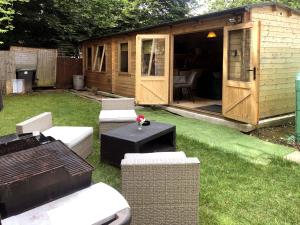 a wooden shed with a table and chairs in a yard at Cosy Garden Log Cabin in Salisbury