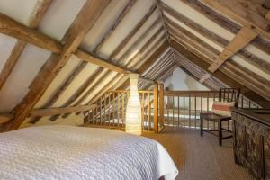 une chambre mansardée avec un lit et une chaise dans l'établissement Acorn Cottage, à Blickling