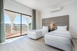 Un dormitorio con dos camas y una gran ventana. en Clube Vilarosa, en Portimão