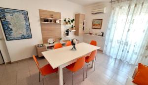 una sala da pranzo con tavolo bianco e sedie arancioni di La Mandronia B&B ad Alghero