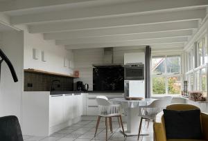 - une cuisine avec des placards blancs, une table et des chaises dans l'établissement Zijper Eilant House, à Oudesluis