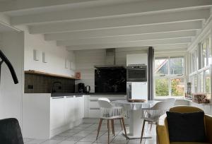 OudesluisにあるHouse on park "Zijper Eilant"の白いキャビネットとテーブルと椅子のあるキッチン