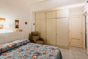 a bedroom with a bed and a chair and a closet at Coralie House in Giardini Naxos