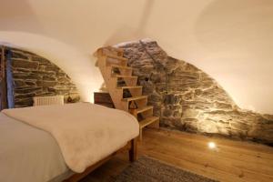 Cette chambre comprend un lit et un mur en pierre. dans l'établissement Charmante maison de hameau traditionnel montagnard, à Saint-Marcel