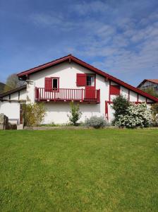 Biały dom z czerwonymi oknami i zielonym dziedzińcem w obiekcie Bortabaratzea 2 w Saint-Pée-sur-Nivelle