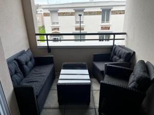 un balcone con 2 divani, un tavolo e una finestra di Appartement de standing avec parking privé a Cherbourg en Cotentin
