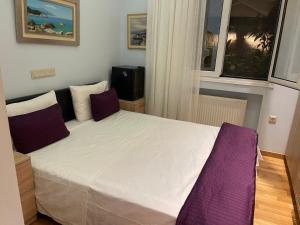 a bedroom with a large white bed with purple pillows at Eleonora's Hidden Gem in Athens