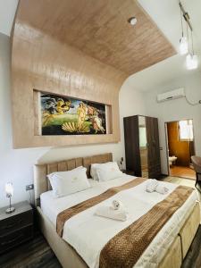 a bedroom with a large bed with a painting on the wall at Prince of Lake Hotel in Shkodër
