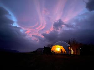 a lit up dome tent under a cloudy sky at Aurora Dome on the South Coast in Hvolsvöllur