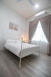 1 dormitorio con cama blanca y ventana en Romi Homestay Wakaf Tapai, en Marang