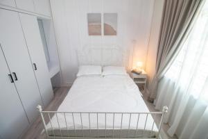 a white bedroom with a white bed and a window at Romi Homestay Wakaf Tapai in Marang