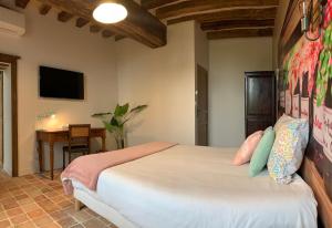 a bedroom with a bed and a desk and a television at LE BAS CHITRAY in Ménil
