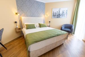 a bedroom with a large bed and a blue chair at Hotel Dolenjc in Novo Mesto