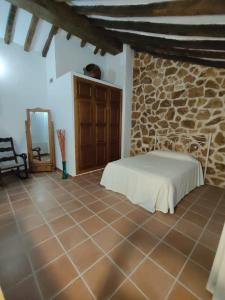 a bedroom with a bed and a stone wall at Casa Gomez in Gaucín