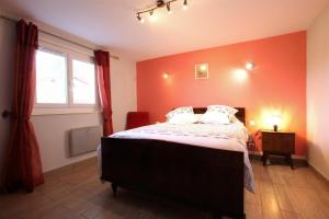 1 dormitorio con paredes de color naranja y 1 cama con 2 almohadas en Celhaya, en Mouguerre