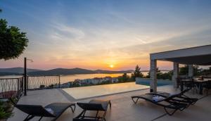 a patio with chairs and a pool with a sunset at Villa GRC in Zaboric