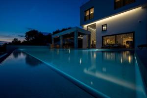 - une piscine en face d'une maison la nuit dans l'établissement Villa GRC, à Žaborić