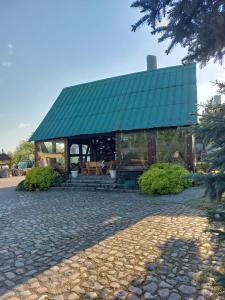 a house with a green roof on a cobblestone street at Milena -Noclegi in Pożrzadło