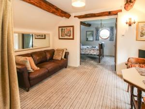 ein Wohnzimmer mit einem braunen Ledersofa und ein Schlafzimmer in der Unterkunft The Beehive in Crewe
