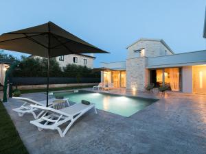 a pool with two lounge chairs and an umbrella at Vila Maslina in Nova Vas
