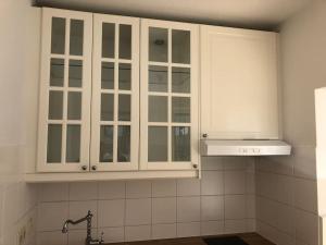 eine Küche mit weißen Schränken und einem Waschbecken in der Unterkunft Perfektes Appartement am Düsseldorfer Rhein in Düsseldorf