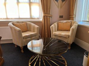 sala de estar con 2 sillas y mesa de cristal en Chester Court Hotel en Chester